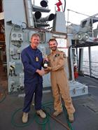 Captain Nick Hine presents Petty Officer (Air Crewman) Leigh Williams with a bottle of champagne