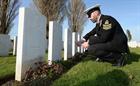 POAET Thomas Fox lays a cross at the grave of a British sailor at Tyne Cot cemetary