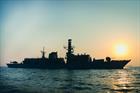 HMS Montrose on patrol at sunset with a tanker in the distance