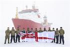 HMS Protectors sailors and Royal Marines unfurl the White Ensign in the Arctic